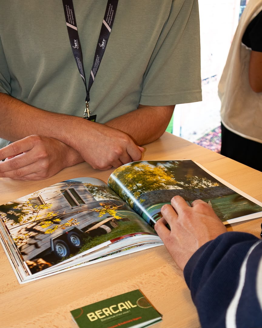 Présentation d'un catalogue de tiny houses à un visiteur